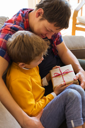 Father's day holiday. Cute young boy is giving a handmade gift box to his dad. Happy family, time together, stay at home.の写真素材