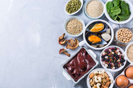 Healthy nutrition dieting concept. Assortment of foods high in iron. Beef liver, spinach, eggs, legumes, nuts, mushrooms, quinoa, sesame, pumpkin seeds, soy beans, seafood. Copy space, flat layの写真素材