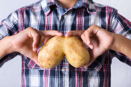 Trendy ugly vegetable, funny potato with imperfect human lungs shape in hands. Farmers produce, organic, misshapen weird food waste concept. Top view, copy space backgroundの写真素材