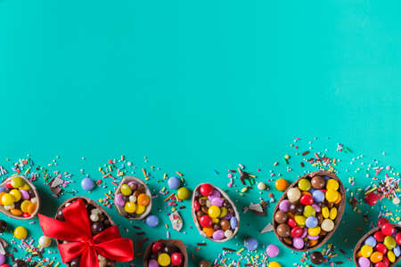 Easter frame with chocolate eggs and sweets on a turquoise, green, blue background. Copy space, top view, flat layの写真素材