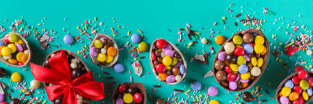 Easter frame with chocolate eggs and sweets on a turquoise, green, blue background. Banner, top view, flat layの写真素材
