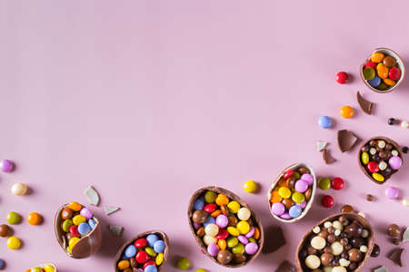 Easter frame with chocolate eggs and sweets on a pink background. Copy space, top view, flat lay