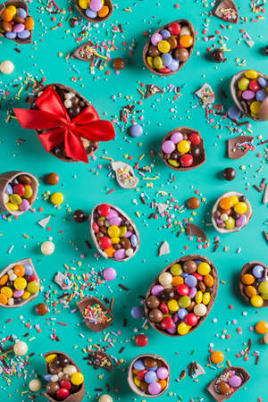 Easter frame with chocolate eggs and sweets on a turquoise, green, blue background. Top view, flat layの写真素材