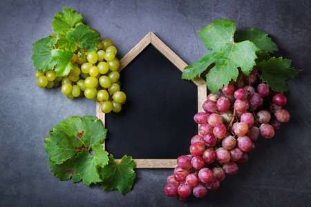 Food and drink, harvest autumn fall concept. Wine tasting, degustation, invitation card with grape vine. Copy space black backgroundの写真素材