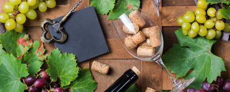 Food and drink, harvest autumn fall concept. Wine tasting, degustation, invitation card with symbols - grape vine, bottle, glasses, corkscrew. Wooden background, bannerの写真素材