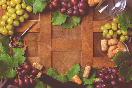 Food and drink, harvest autumn fall concept. Wine tasting, degustation, invitation card with symbols - grape vine, bottle, glasses, corkscrew. Wooden background, tonedの写真素材