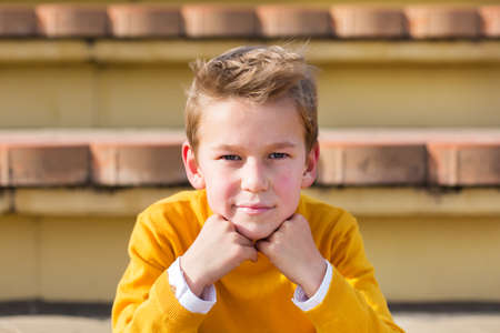 Stylish young boy, teenager is sitting at the stadium, outdoorsの写真素材