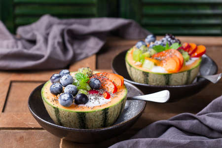 Fruit salad with yogurt in carved melon cantaloupe bowl