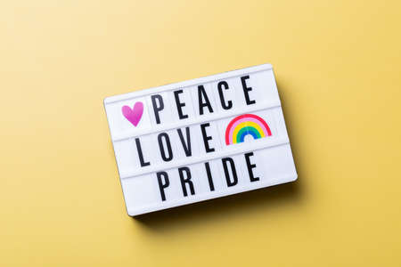 Peace love pride text, rainbow lgbtq flag against yellow background
