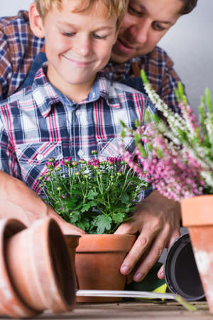 Child helps to father planting flowers. Family time at homeの写真素材