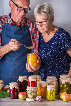 Senior couple holding in hands preserved foodの写真素材