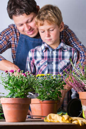 Child helps to father planting flowers. Family time at home