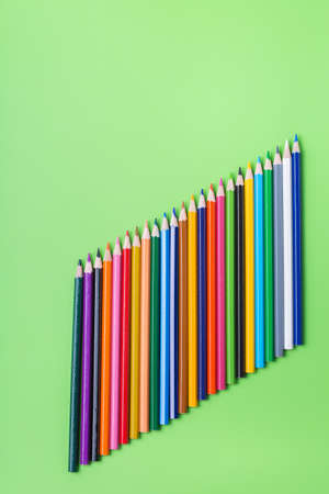 Colourful rainbow pencils and alarm clock on lime green backgroundの写真素材