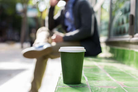 Man walking on the street, drinking coffee, talking by phoneの写真素材