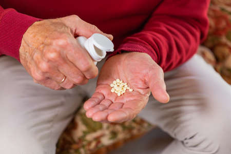 Senior man taking medicine, pills, supplement, closeup of handsの写真素材