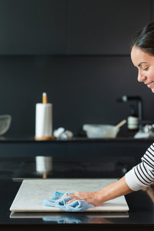 Woman cleaning the table while cooking at the kitchenの写真素材
