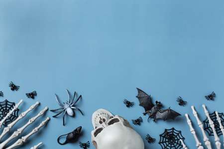 Halloween greeting card with pumpkin, skulls, bony hands and leaves