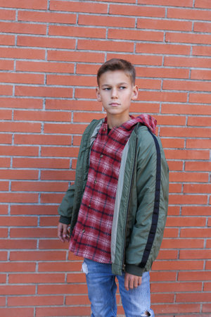 Young boy standing against a brick wallの写真素材