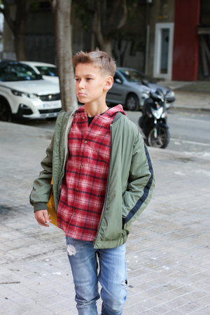 Handsome teenager walking on the city street, outdoors. Caucasian young boy going home in his neighbourhoodの写真素材