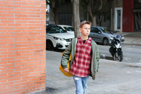 Handsome teenager walking on the city street, outdoors. Young boy going home in his neighbourhoodの写真素材