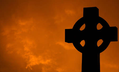 A Silhouette of a Cross with Clouds at Sunsetの写真素材