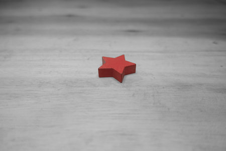 Red star on a white wooden background. Selective focus. Toned.