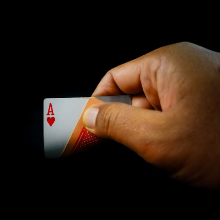 playing card in hand on black background with copy space for text or imageの写真素材