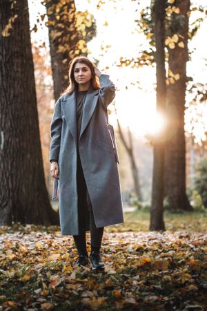 Pretty girl walking in autumn park. Beautiful autumn sunny weather. Young woman enjoying fall. Women fashion. Autumn holidays. People, autumn and lifestyle concept.の写真素材