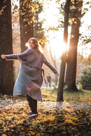 Pretty girl walking in autumn park. Beautiful autumn sunny weather. Young woman enjoying fall. Women fashion. Autumn holidays. People, autumn and lifestyle concept.の写真素材
