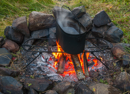 Tourist kettle with boiled water over campfire with firewoodの写真素材