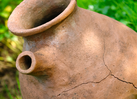 Old clay pot with cracks on grassの写真素材