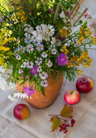 Still life: bouquet of wildflowers in clay vase and fruitsの写真素材