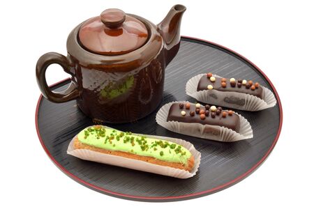 Teapot and three eclairs on black tray