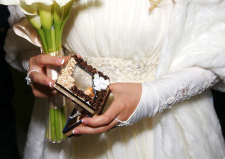 Box with wedding rings and white bouquet in hands of brideの写真素材