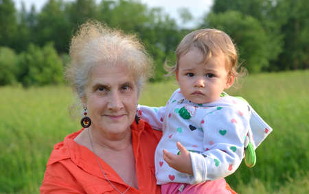 Grandmother with her granddaughter in her arms in summer park