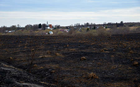 Village view across scorched field in early spring, village of Zinovyevo, Vladimir region, Russiaの写真素材
