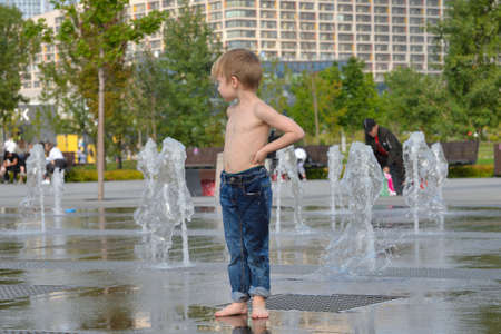 Moscow, Russia, August 28, 2021: Little boy running among fountains on hot sunny day in Khodynskoye field - Moscow park in southern part of historic area of same nameのeditorial素材