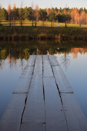 Wooden bridge on pond in autumn parkの写真素材