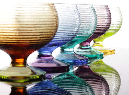 Five colored glasses with reflection on a tableの写真素材