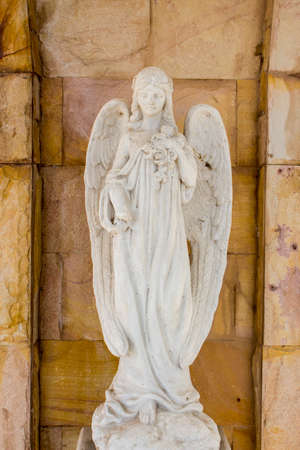 Old white angel statue in the church with stone wall background.の写真素材