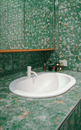interior view of modern bathroom with green tiles and foreground on the washbasin and on the white faucetのeditorial素材