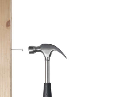 hammer isolated on a white background while pulling out a nail from a piece of woodの写真素材