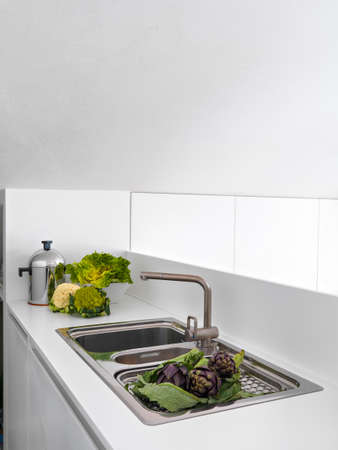 vegetables on the steel worktop near to faucet in the modern kitchenの写真素材