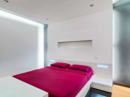 interior view of a modern bedroom whosebedspreads and linens are red colorの写真素材