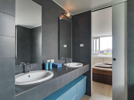 interior view of a modern bathroom in foreground two Vanity vsin overlooking on the bedroomの写真素材