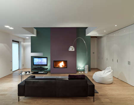 interior view of a modern living room with leather sofa in front of the fireplace  whose floor is made of woodの写真素材