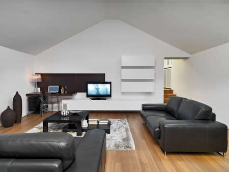 interior view of a modern living room in the mansard in foreground the leather sofa and wooden floorの写真素材