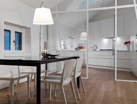 interior view of a modern living room in foreground the dining table overlooking on the kitchen whose floor is made of woodの写真素材