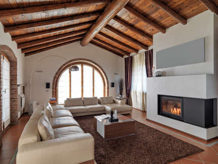 foreground of a leather sofa and  fireplace in the modern living room with tile floor and wood ceilingの写真素材