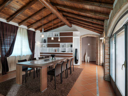 interior view of a modern dinnig room in the penthouse in foreground the dining table with chairs whose fllor is made of terracotta tilesの写真素材